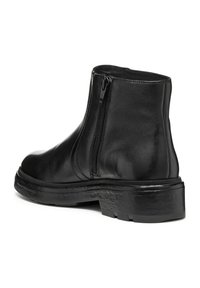 Bottines en cuir noir avec une fermeture éclair sur le côté, à bout rond et semelle en caoutchouc noir texturé. Surface lisse avec finition brillante.