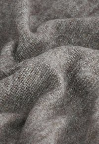 Tissu gris en laine douce et froissée avec une texture finement tricotée et serrée, présenté en gros plan.