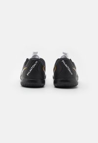 Zwarte sportieve schoenen met een gestructureerd oppervlakte, witte en gouden accenten, met "PHANTOM" branding op de hak en een ronde zoolontwerp.