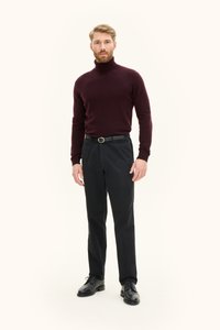 Bordeauxroter Rollkragenpullover, schwarze Hose und schwarze Lederschuhe. Der Pullover hat einen gerippten Saum und Bündchen; die Hose ist mit einem Gürtel versehen.