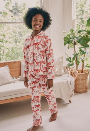 Røde og hvide mønstrede pyjamas med sløjfer, prikker og striber, lavet af blødt stof. Langærmet og buksedesign, afslappet pasform.
