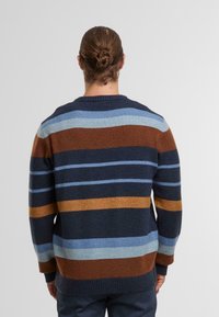 Maglione a maglia con strisce orizzontali in marrone, blu e oro. Il design presenta un colletto e polsini a coste con una vestibilità ampia e rilassata.