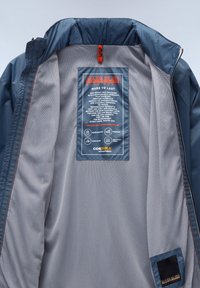 De binnenkant van de Napa Puri-jacket heeft een blauwe nylon voering met een meshstructuur. Inclusief een onderhoudsetiket en merklabel. Waterproof en ademend.