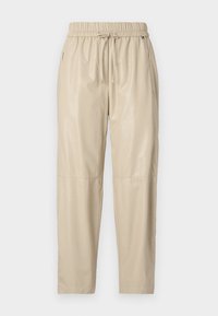 Beige joggerbroek gemaakt van glanzend, glad materiaal. Voorzien van een elastische tailleband met trekkoord, zijzakken en taps toelopende pijpen.