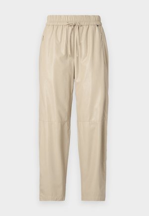 Beige joggerbroek gemaakt van glanzend, glad materiaal. Voorzien van een elastische tailleband met trekkoord, zijzakken en taps toelopende pijpen.