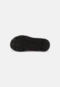 Suela de zapato de goma negra con un patrón de relieve en espiga. Diseño de punta redondeada con un talón ligeramente elevado y superficie plana.