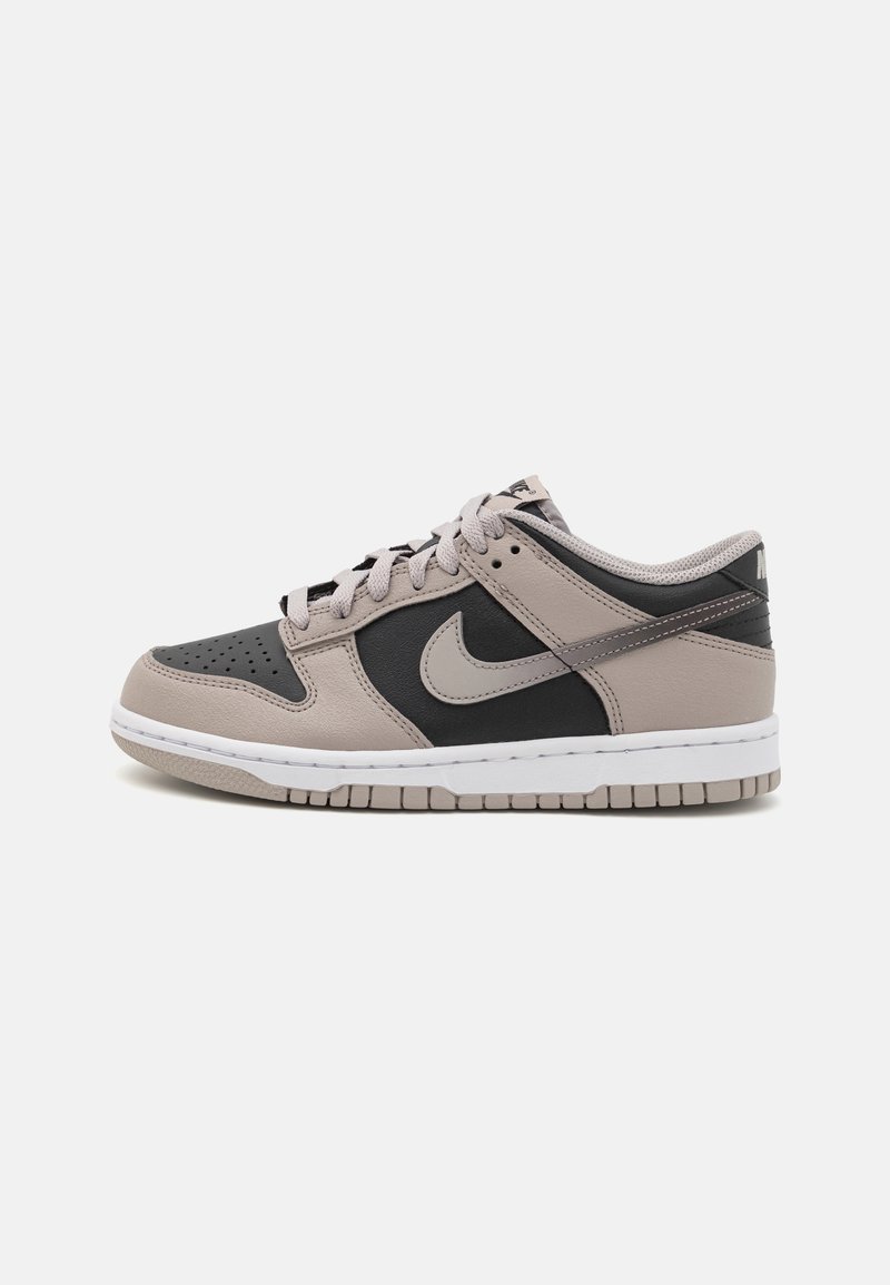 Nike Dunk sneakers in black and beige leather with a white sole, featuring perforated toe, laces, and a recognizable swoosh logo.