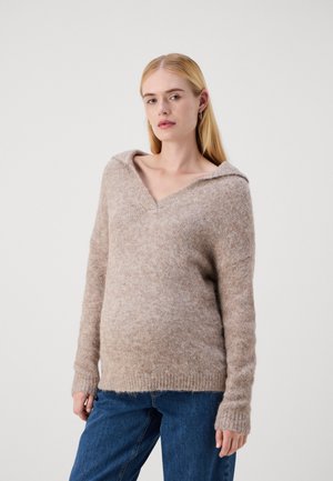 Beige knitted sweater with a hood, featuring a v-neck, long sleeves, and ribbed cuffs. Soft texture and relaxed fit. Worn with blue jeans.