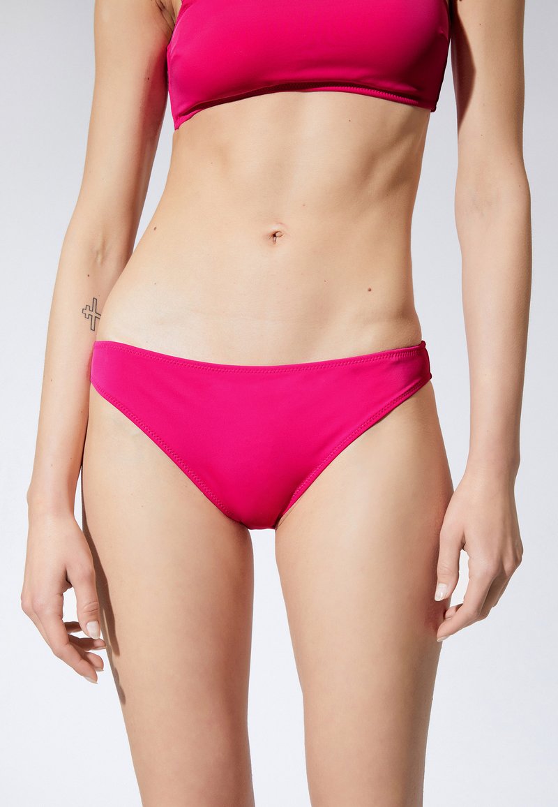 Jasnoróżowy bikini, o prostym fasonie, wykonane z gładkiego, elastycznego materiału o klasycznym kroju z niskim stanem i minimalną ilością szwów.