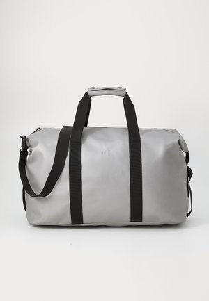 Gray duffel bag with black straps, featuring a top handle and zipper closure, set against a plain white background.