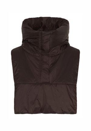 Femme portant un manteau noir croisé, un jean large bleu foncé avec des liens aux chevilles, des chaussures noires et une écharpe à capuche marron.