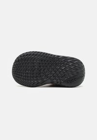 Suela de zapato de goma negra con un patrón de diamante texturizado para tracción. Presenta acentos elevados y "Reebok" grabado en el talón.