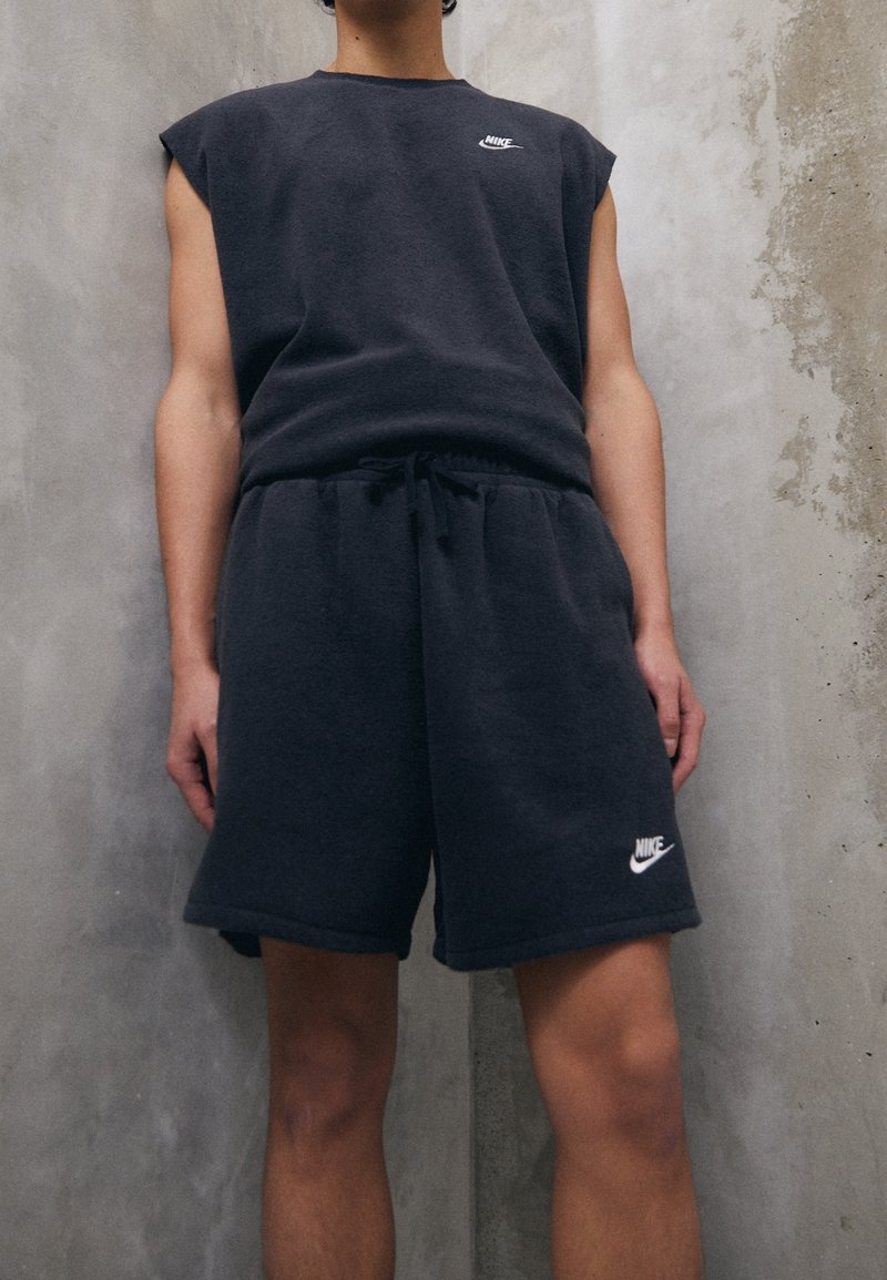 Conjunto de top sin mangas y shorts de mezcla de algodón en gris oscuro, con un diseño ajustado y el logo de Nike en blanco en el pecho y el dobladillo.