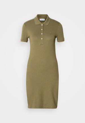 Olíva zöld pólódressz puha anyagból készült, galléros nyakkivágással, rövid ujjakkal és diszkrét márkajelzéssel ellátott gombos felső résszel rendelkezik.