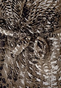 Tissu marron et noir à motif avec une ceinture à nouer, présentant une surface texturée et un dessin de lignes ondulées.