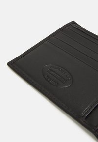 Le porte-cartes en cuir noir présente plusieurs emplacements pour cartes, un logo embossé et une couture contrastante le long des bords. Texture lisse.