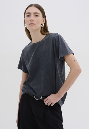 T-shirt grigio carbone con una vestibilità comoda, scollo rotondo e maniche corte. Presenta un ricamo discreto sul petto e una texture morbida.