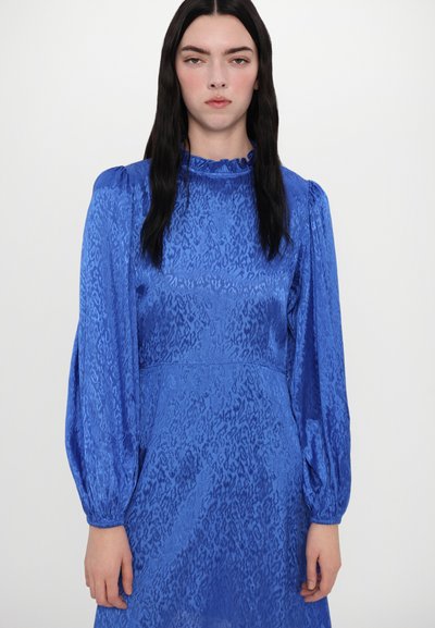 Blauwe jurk met een gestructureerde afwerking, met lange opgezette mouwen en een ruchesnek. Het ontwerp heeft een subtiel dierenprintpatroon.