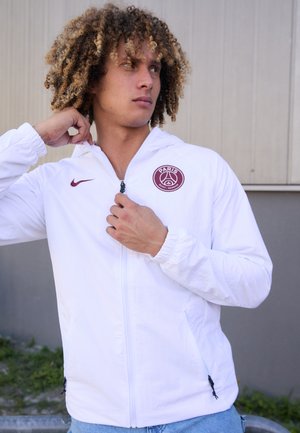 Witte zip-up jas met capuchon, voorzien van een maroon Paris Saint-Germain logo op de borst en een klein Nike swoosh op de schouder.