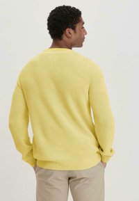 Gelber, gestrickter Pullover mit Rippstruktur, Rundhals und langen Ärmeln. Hat eine lässige Passform und dezente Säumdetails.