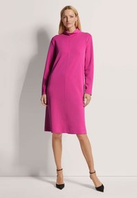 Fuchsia Kleid mit hohem Kragen, langen Ärmeln, geradem Schnitt und knielangem Saum. Glatte Stofftextur, minimale Nahtdetails.