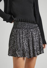 Svart och grå leopardmönstrad kjol med smockad midja och volangkant, tillverkad av lättviktsmaterial. Matchad med en texturerad svart topp.