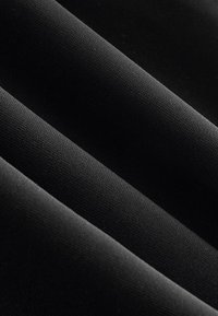 Zwart geweven textiel met meerdere plooien, een gladde textuur en een lichte glans, die diepte creëert met variaties in licht en schaduw.