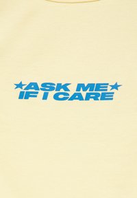 Texte bleu indiquant "ASK ME IF I CARE" avec des étoiles de chaque côté sur un fond uni jaune clair.