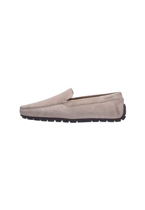 Beżowe mokasyny typu slip-on z zamszu z czarną gumową podeszwą i detalem szwu, widok z boku pokazujący niski obcas i nazwę marki wytłoczoną w pobliżu pięty.