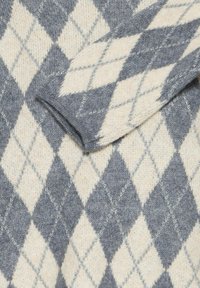 Maglione lavorato a maglia con un motivo argyle grigio e crema, dalla consistenza morbida e con un sottile contorno grigio chiaro attorno alle forme a rombo.
