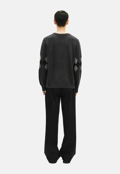 Suéter gris de punto con patrones de diamante en las mangas, cuello redondo y un corte relajado, combinado con pantalones negros amplios. Vista posterior.