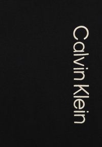 Tessuto nero con la scritta "Calvin Klein" in grandi lettere bianche ricamate sul lato sinistro, che mostra una texture liscia e uniforme.