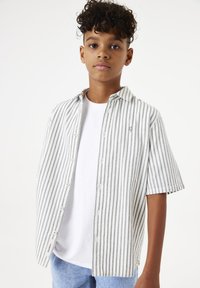 Korte mouwen, knoopshirts in wit met grijze verticale strepen. Bevat een casual kraag en logo-detail, gedragen over een wit T-shirt.