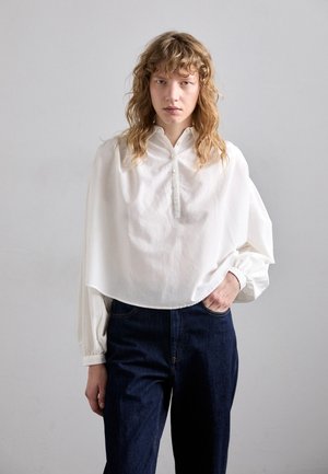 Witte katoenen bloes met een kraag en knoopsluiting, met een losse pasvorm en ingezette mouwen. Gepaard met donkerblauwe wijde jeans.
