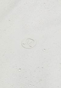 Gouttes d'eau sur un tissu blanc lisse avec un logo circulaire Lululemon centré embossé sur la surface.
