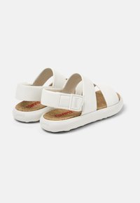 Vita sandaler i vitt med tre breda remmar, korkfotbädd och en texturerad gummisula med "Camper"-logotypen i rött på innersulan.