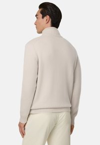 Krämfärgad, ribbad turtleneck-tröja med en mjuk textur. Baksidan har en sömlös design och en avslappnad passform.