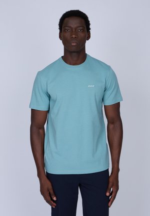 T-shirt à manches courtes bleu clair en mélange de coton, présentant un col rond et un logo blanc discret sur la poitrine gauche. Texture lisse, coupe décontractée.