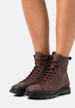 Brązowe skórzane buty za kostkę z sznurowaniem o eleganckim designie, wysoką cholewką i czarną gumową podeszwą z teksturowanym bieżnikiem dla lepszej przyczepności.