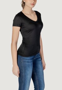 Sort T-shirt med korte ærmer og V-hals, lavet af blødt stof, tætsiddende form, parret med blå jeans med klassisk design og subtile syninger.