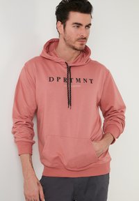 Felpa con cappuccio rosa tenue, dotata di tasca frontale, con logo nero "DPRTMNT" e lacci decorativi a contrasto. Realizzata in un mix di cotone.