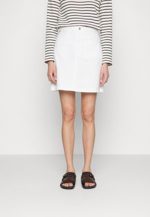Gonna di denim bianca con chiusura a bottoni frontale e tasche, abbinata a una blusa a righe con maniche lunghe e sandali marroni. Tessuto liscio.