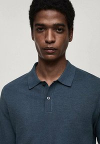 Tmavě modrý polo triko s texturovaným pletením, dvouknoflíkovou légou a klasickým límečkem. Tričko má slim fit střih a minimální detaily.