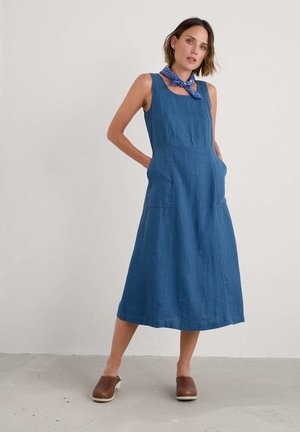 Sinine linane ilmaülikonna rõ dresses on kinnitatud bodice, kahe esitasku ja laieneva seeliku, millele on lisatud sinine mustriga sall ja pruunid puukingad.