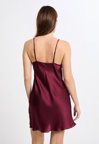 Vestido de satén burdeos tipo slip con tirantes finos ajustables, que presenta una textura suave y brillante y un dobladillo acampanado.