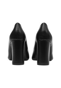 Un paio di scarpe nere in pelle con tacco alto viste da dietro, caratterizzate da tacco a blocco e cuciture verticali lungo la cucitura del tallone.