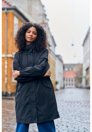 Parka noire imperméable avec un col haut, une capuche à cordon de serrage et des poignets élastiques. Comprend des poches avant et un design épuré et minimaliste.