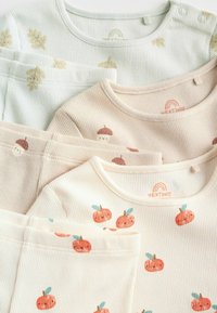 Vier gerippte Baumwolltops für Kleinkinder in Pastellfarben; grün mit Blättern, beige mit Eicheln und cremefarben mit orangefarbenen Kürbissen, alle mit runden Ausschnitten.