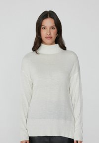 Cremfarbener Rollkragenpullover aus weichem, leichtem Material. Mit langen Ärmeln, gerippten Bündchen und Saum sowie einer lockeren Passform.
