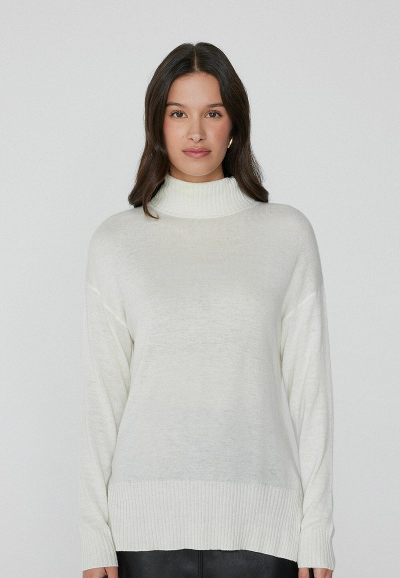 Cremfarbener Rollkragenpullover aus weichem, leichtem Material. Mit langen Ärmeln, gerippten Bündchen und Saum sowie einer lockeren Passform.